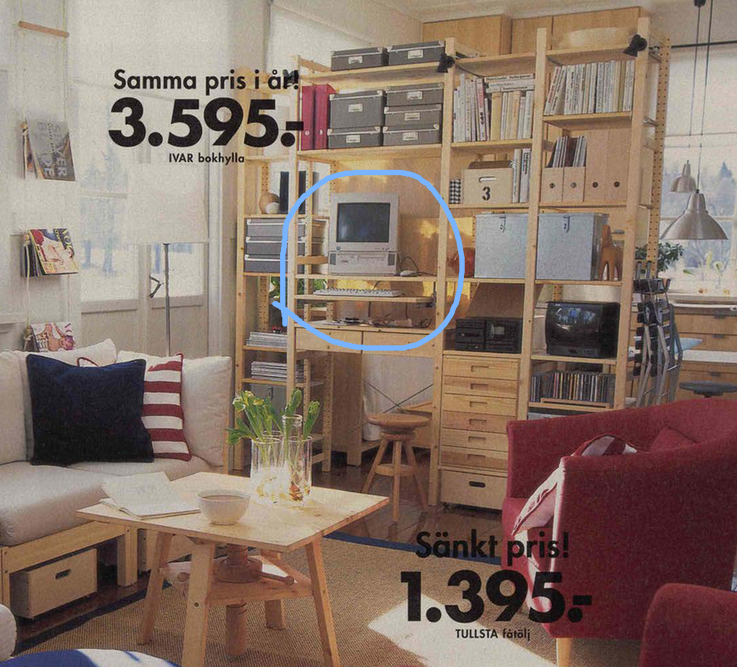 Extract from the 1997 Ikea catalogue. An IVAR shelf combination is staged in a modern, uncluttered living room, warn and brightly lit. The shelves are filled with miscellaneous office items, I made a blue circle mark around the part of the photo with the old computer setup, complete with a CRT monitor, and a keyboard and mouse on the aforementioned IVAR keyboard tray